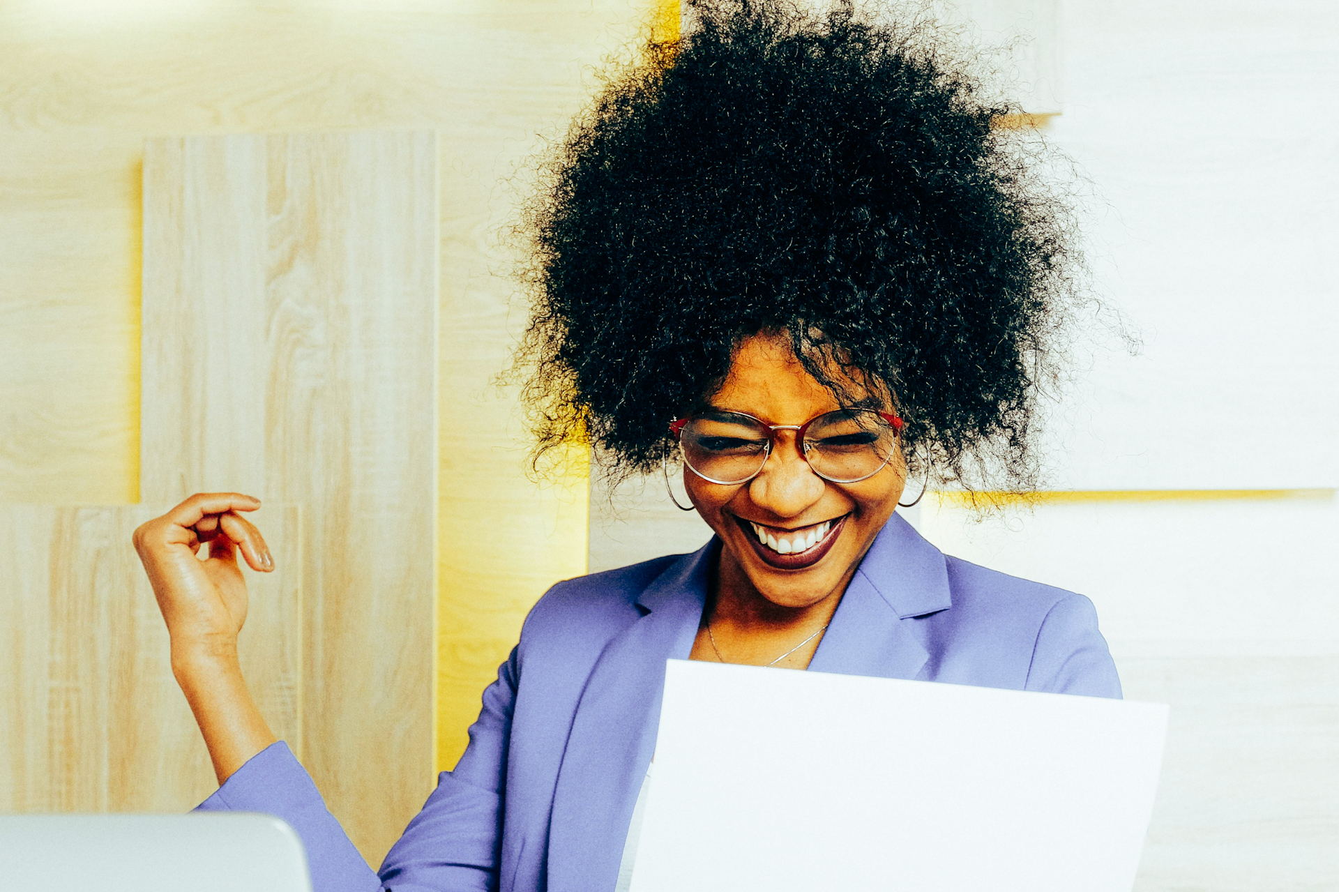 an image of a lady, sat in front of her laptop, celebrating