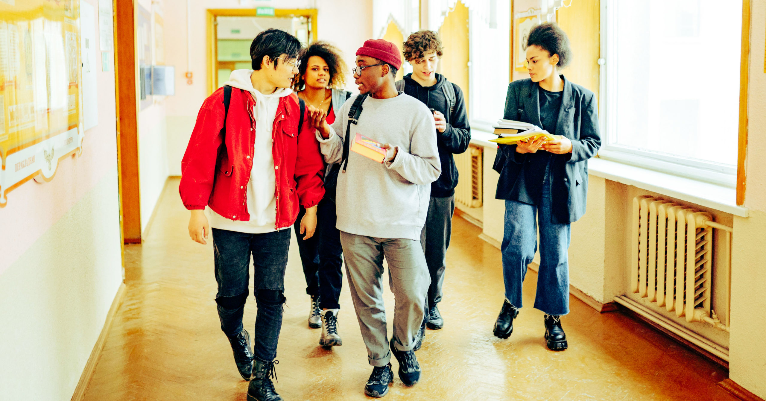 a group of young adults walking down the corridor of a college